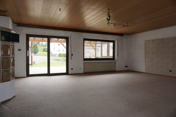 Wohnung EG - Wohnzimmer mit Kachelofen und Zugang zur Terrasse